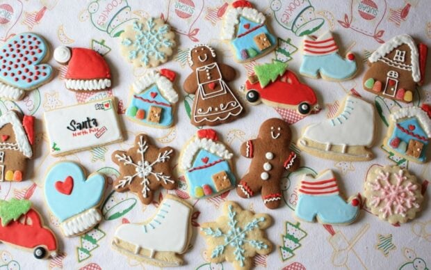 Assorted festive gingerbread house cookies and holiday shapes decorated with colorful icing