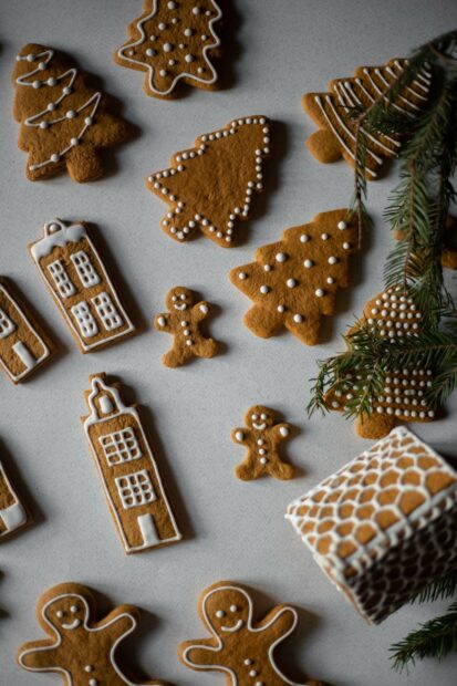 Gingerbread cookies shaped like trees and gingerbread men decorated with white icing on a gray surface