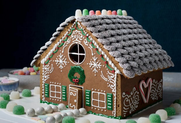 A detailed gingerbread house decorated with festive icing and colorful candies on a white surface