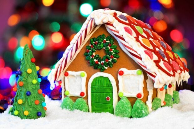 A festive gingerbread house decorated with icing and candies in a snowy setting