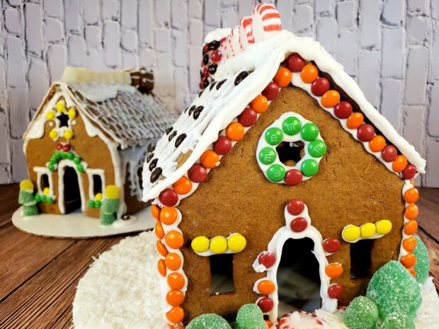 A gingerbread house decorated with colorful candy on a wooden surface