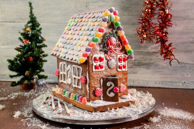 A colorful gingerbread house decorated with candy and icing on a wooden table