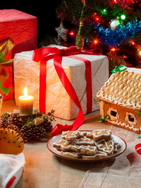 A gingerbread house surrounded by Christmas cookies and festive decorations on a holiday table