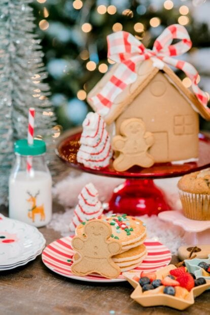 A gingerbread house with festive cookies and decorations on a holiday table