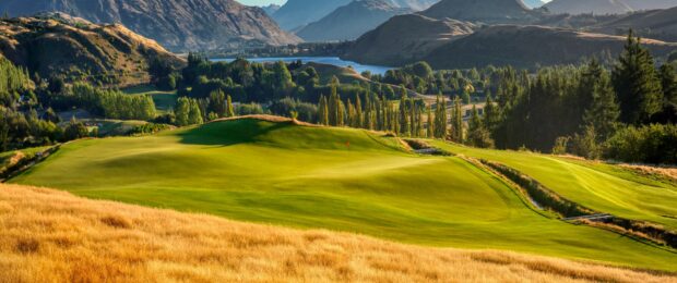 A beautiful golf course surrounded by hills and trees under clear blue sky