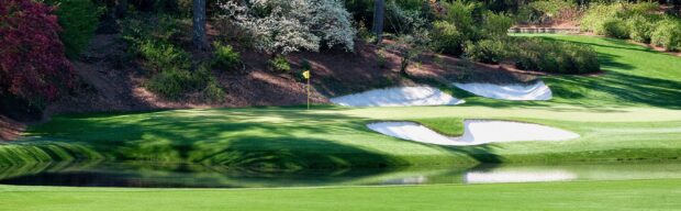 A golf course with sand bunkers and a small pond surrounded by trees and greenery