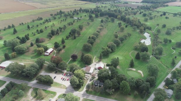 Aerial view of a golf course with lush green fairways and scattered trees