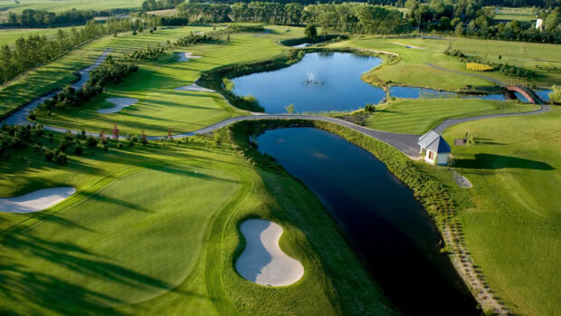A beautifully maintained golf course with green fairways and water hazards on a sunny day