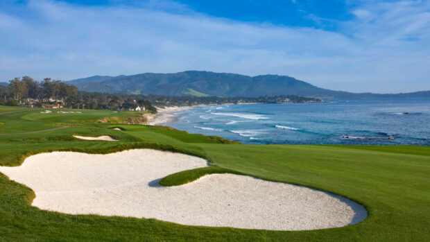 A golf course with green fairways and sand bunkers beside a scenic ocean coastline