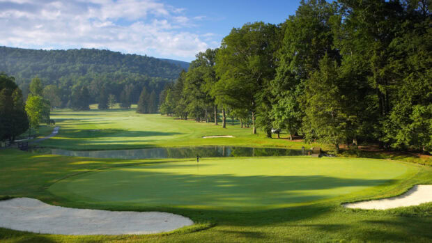 A golf course with green fairways and trees on a sunny day in the countryside
