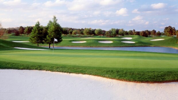 A golf course with green grass and sand traps under a partly cloudy sky
