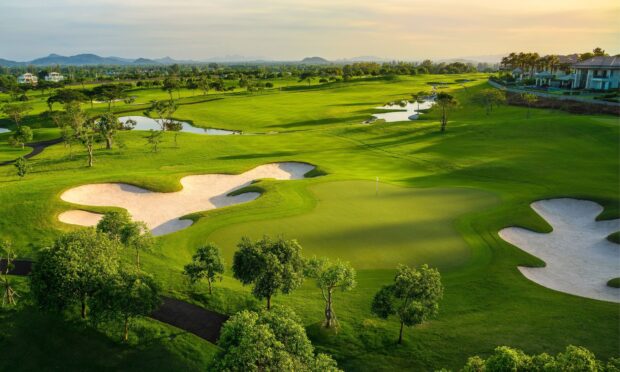 A scenic golf course with green fairways and sand traps under a clear sky