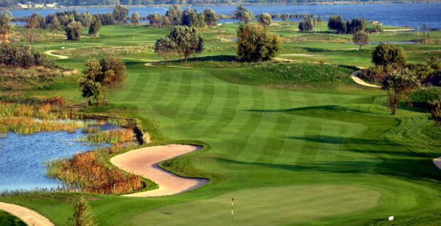 A beautiful golf course with trees and water hazards on a sunny day