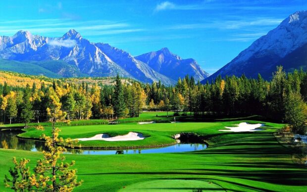 A lush golf course surrounded by trees and mountains in a serene landscape