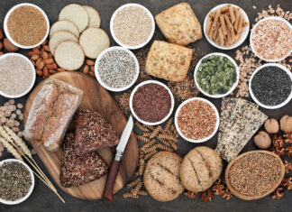 A variety of grains displayed with bread rolls and seeds arranged on a wooden board and bowls