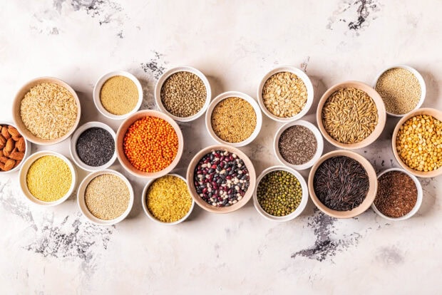 A variety of grains displayed in bowls on a marble surface showcasing different types of grains