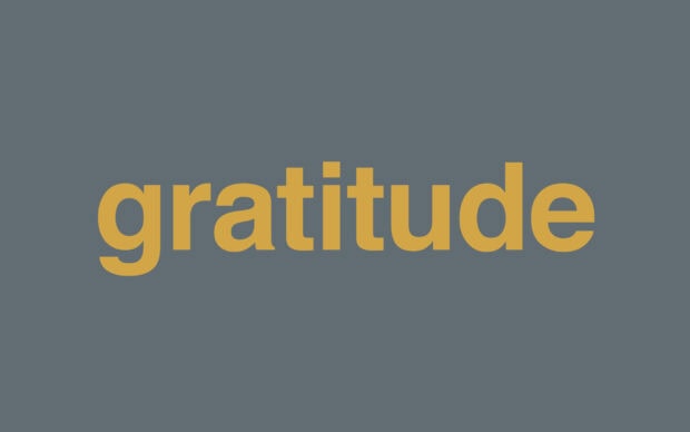 The word gratitude displayed in bold yellow text on a blue gray background