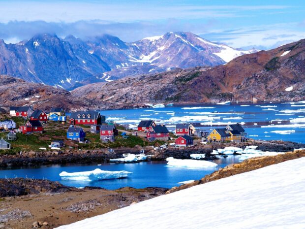 Colorful Greenland village with fjord and icy mountains in summer