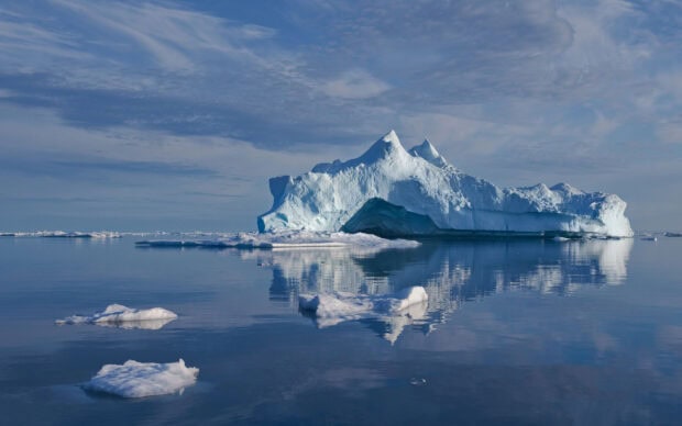 Large iceberg reflecting on calm water in Greenland landscape