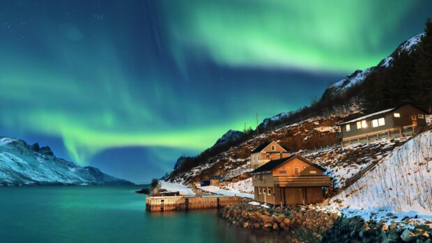 Northern lights above Greenland houses and snowy landscape at night
