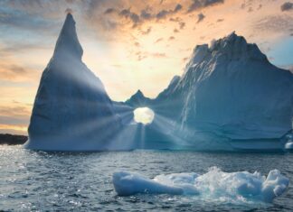 Natural Greenland iceberg formation with sun rays shining through a hole in the ice