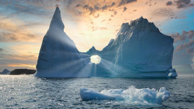 Natural Greenland iceberg formation with sun rays shining through a hole in the ice