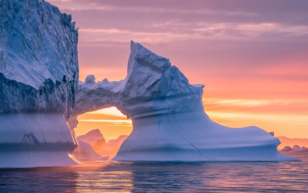 Stunning Greenland iceberg with natural arch during colorful sunset