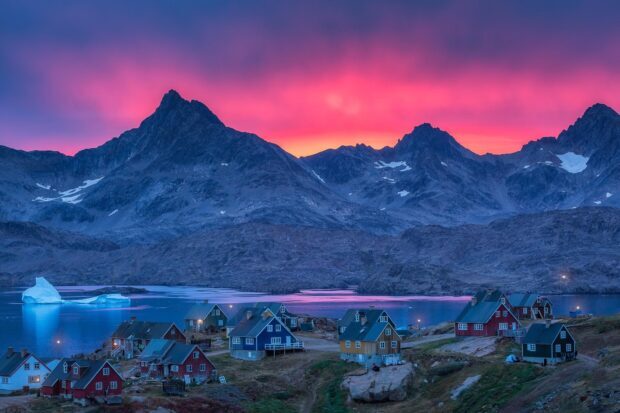Colorful sunset over Greenland village with mountains and iceberg in the distance