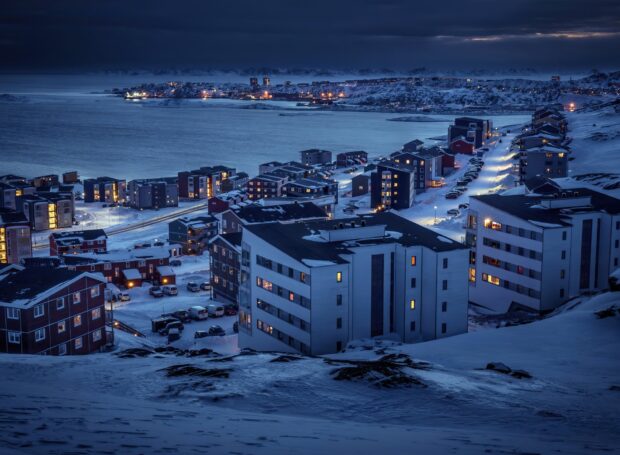 Evening view of Greenland town covered in snow with glowing lights