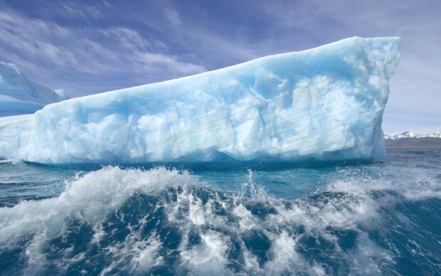 Large Greenland ice formation floating in the sea under a blue sky
