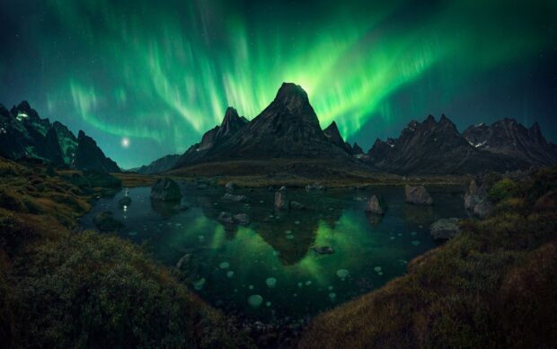 Majestic mountain reflecting in a lake under the northern lights in Greenland