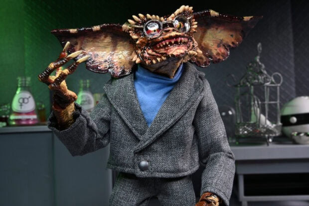 A detailed gremlin character wearing a gray suit and blue turtleneck in a laboratory setting
