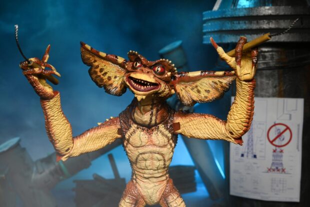 A detailed gremlin figure with large ears and sharp claws holding two sticks
