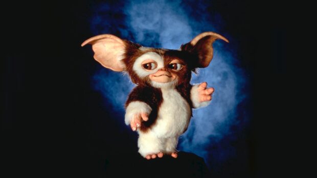 A cute gremlin standing with a blue smoky background and large ears visible