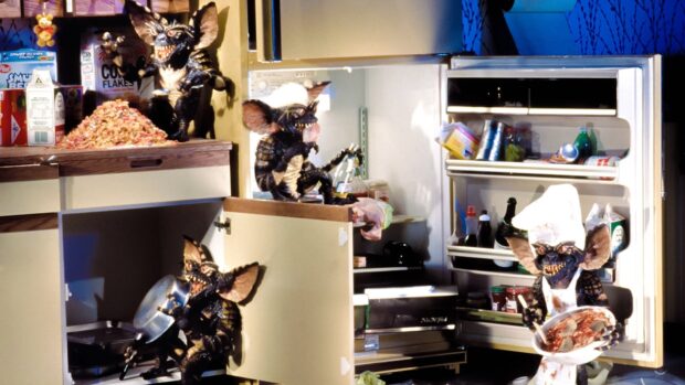 Gremlin creatures mischief in a kitchen with one cooking and others exploring shelves