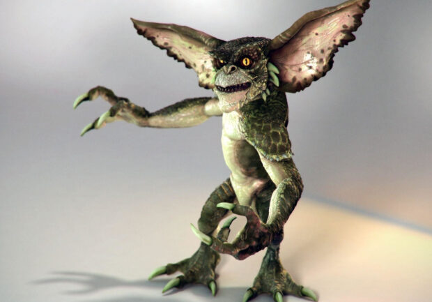 A detailed gremlin creature standing with clawed hands and large ears in a neutral background