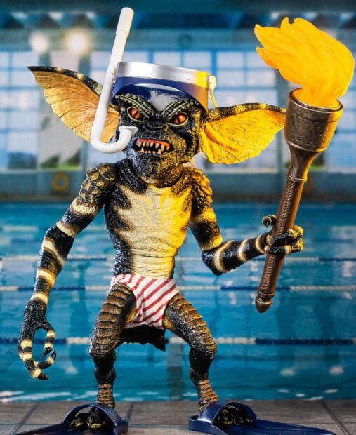 A gremlin figure wearing swimming gear and holding a flaming torch near a pool