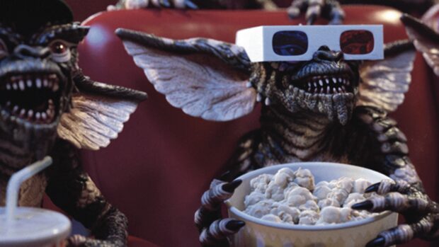 A gremlin wearing 3d glasses enjoying popcorn in a movie theater