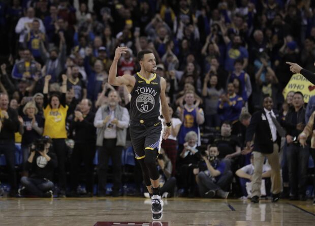Stephen Curry celebrating on the court with excited fans in the background