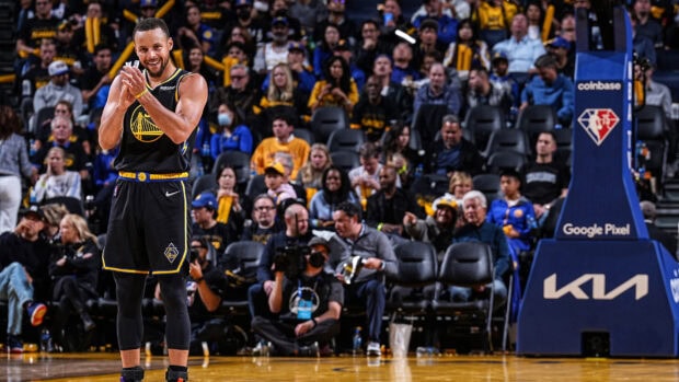 Stephen Curry standing and clapping during a Golden State Warriors basketball game