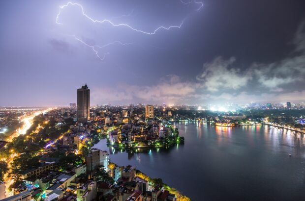 Lightning streaks above the urban skyline of Hanoi at night with West Lake in view