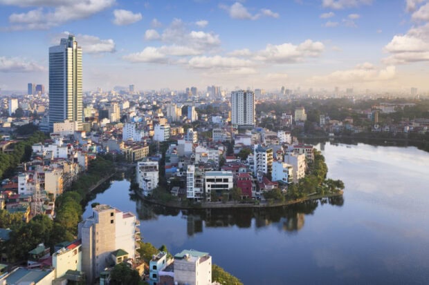 A scenic view of Hanoi cityscape with a river bending around urban buildings and a tall tower in the background