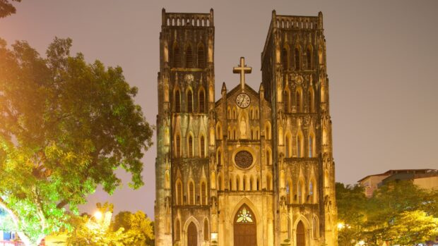 The old Hanoi cathedral illuminated at night with surrounding trees