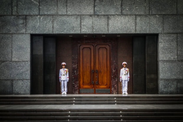 Two honor guards standing at the wooden door entrance in Hanoi