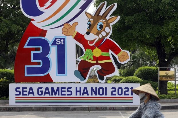 Cartoon mascot celebrating sports event in Hanoi street scene with greenery background