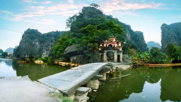 Ancient stone bridge and historic temple surrounded by lush greenery in Hanoi nature scenery