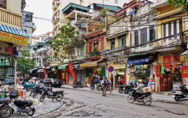 A busy street scene with old buildings and motorcycles in Hanoi street