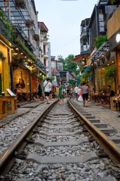People walking along Hanoi railway street on the tracks during the day