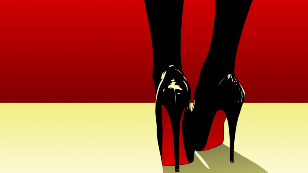 Black high heels with red soles on a red and yellow background