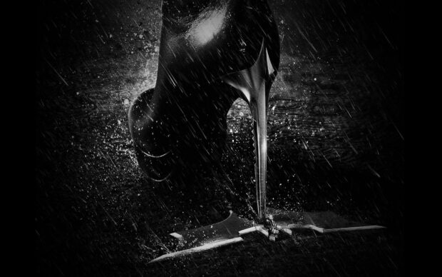 Black high heels stepping on a wet surface with rain droplets around the heel